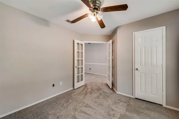 an empty room with closet and a ceiling fan
