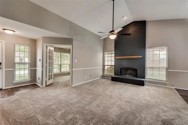 an empty room with windows and fireplace