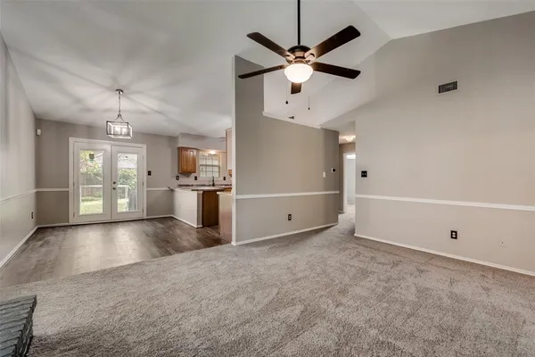 an empty room with fan and way to kitchen