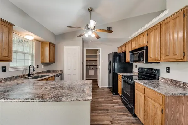 a kitchen with stainless steel appliances granite countertop a stove top oven a sink dishwasher a refrigerator and a oven with wooden floor