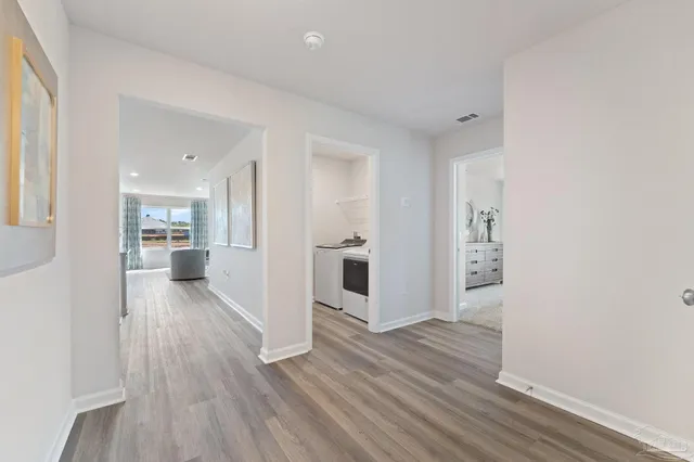 a view of a hallway with wooden floor and a kitchen