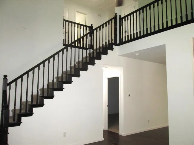 a view of staircase with railing and white walls