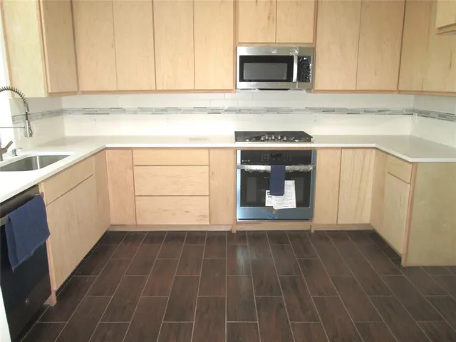 a kitchen with granite countertop a sink a stove and cabinets