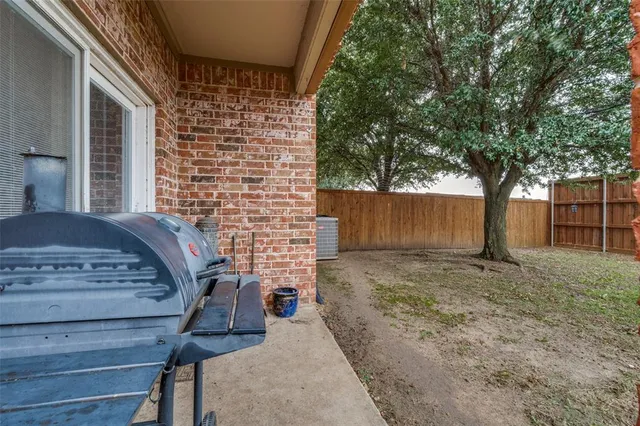a view of a backyard with a large tree and wooden fence