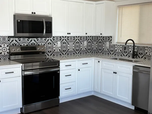 a kitchen with granite countertop white cabinets and black appliances