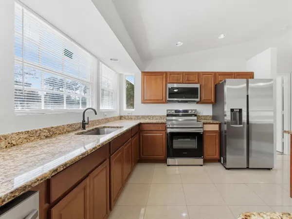 a kitchen with stainless steel appliances granite countertop a stove a sink and a refrigerator