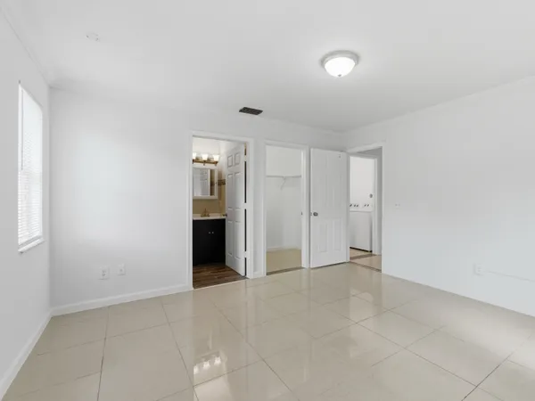 a view of an empty room with kitchen and a window