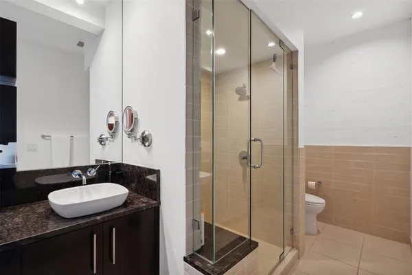 a bathroom with a granite countertop sink a toilet a mirror and shower