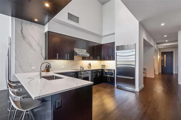 a kitchen with stainless steel appliances a dining table chairs stove and refrigerator