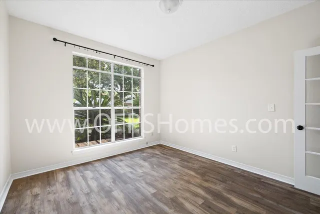 an empty room with wooden floor and windows