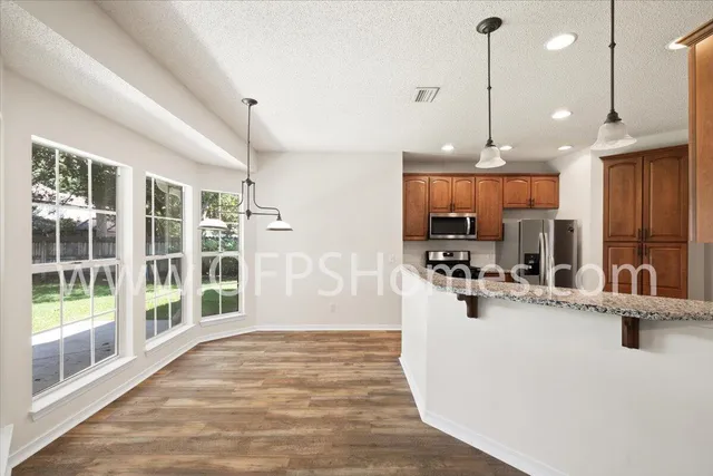 a view of a kitchen with kitchen island a large counter top space a sink stainless steel appliances and cabinets