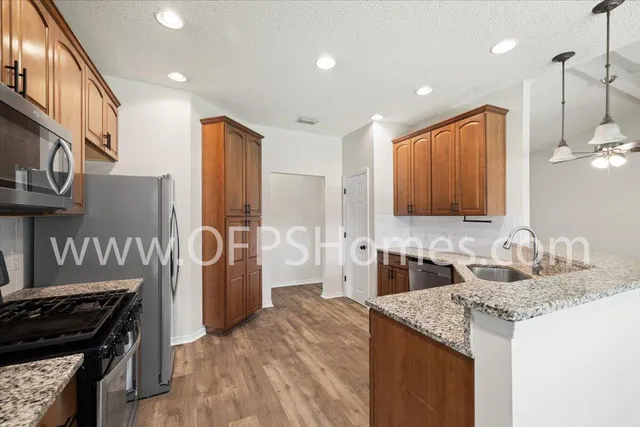 a kitchen with stainless steel appliances granite countertop a sink stove and refrigerator