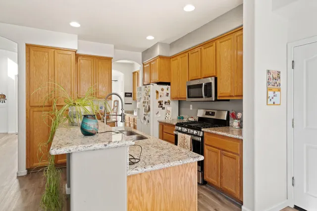 a kitchen with stainless steel appliances granite countertop a sink a stove and a refrigerator