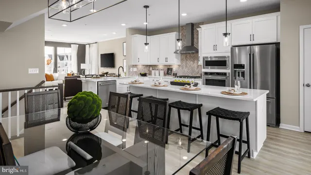 a kitchen with stainless steel appliances kitchen island granite countertop a dining table chairs and a refrigerator