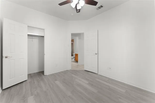 an empty room with wooden floor ceiling fan and windows