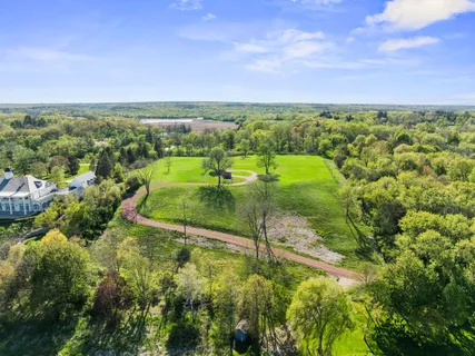 an aerial view of residential houses with outdoor space and trees all around