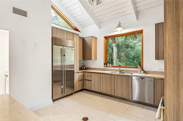 a large kitchen with a window and stainless steel appliances