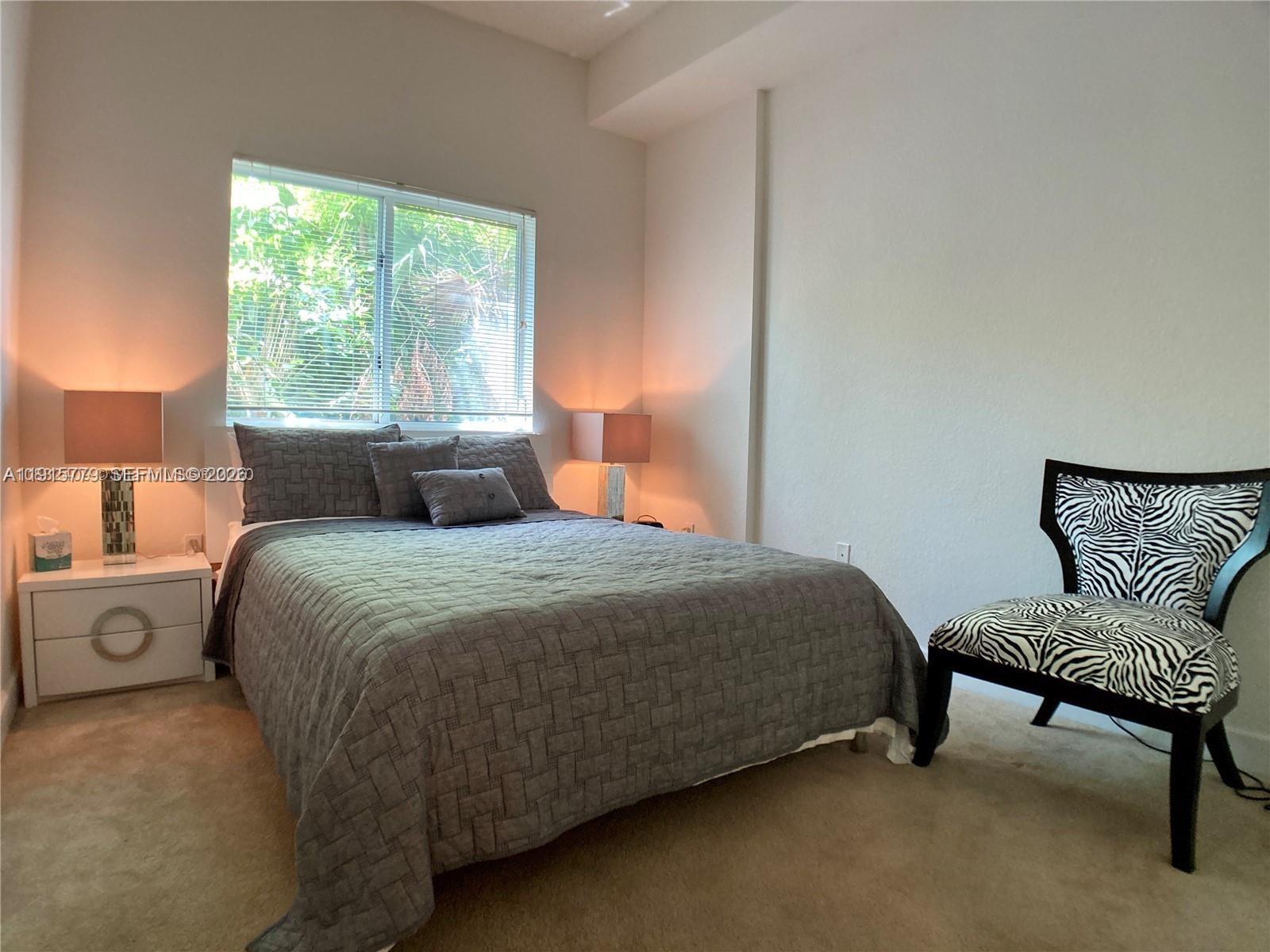 6001 Southwest 70th Street, Unit 115 South Miami, FL 33143 - Photo 11 of 16 a bedroom with a bed and a chair