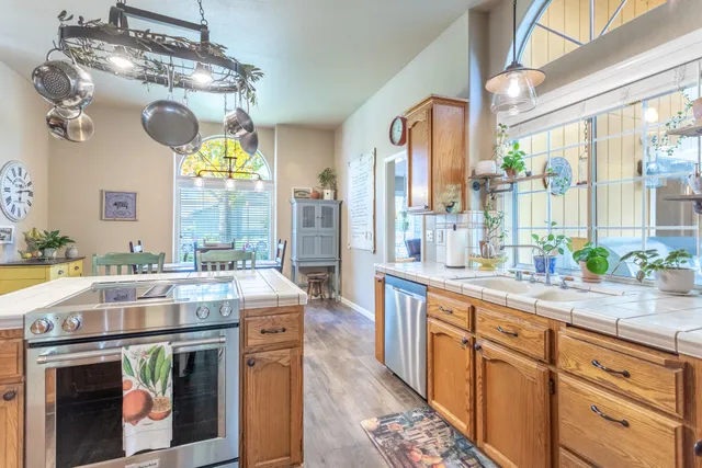 a kitchen with kitchen island granite countertop a stove a sink dishwasher and white cabinets with wooden floor