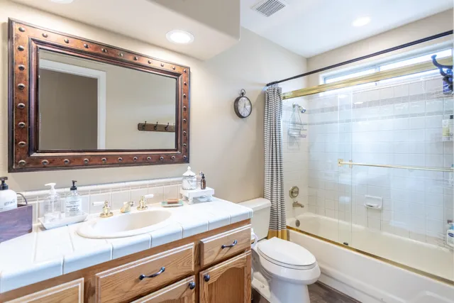 a bathroom with a granite countertop sink toilet mirror and shower