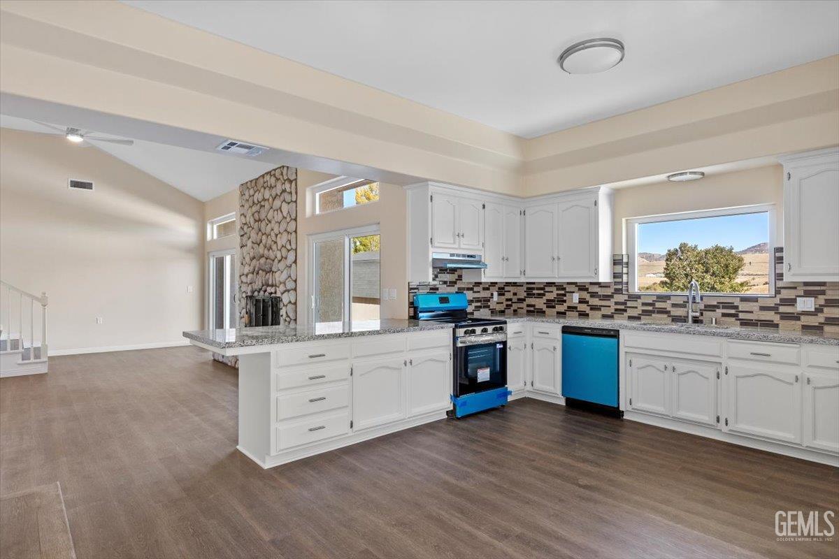 Undisclosed Address Tehachapi, CA 93561 - Photo 13 of 40 a kitchen with granite countertop a stove a sink and white cabinets with wooden floor