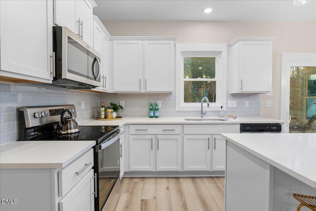 1917 Essex Road, Unit A Durham, NC 27704 - Photo 12 of 26 a kitchen with stainless steel appliances granite countertop a sink stove and cabinets
