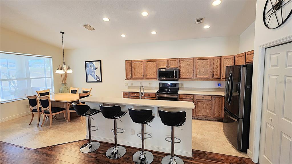 1636 West Caroline Path Lecanto, FL 34461 - Photo 38 of 85 a kitchen with stainless steel appliances kitchen island granite countertop a refrigerator a stove a sink a dining table and chairs with wooden floor