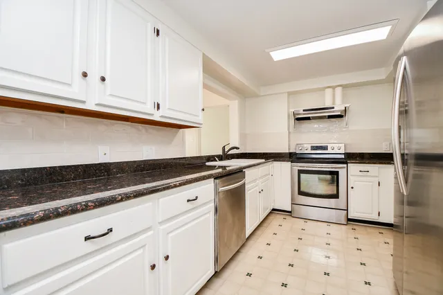 a kitchen with granite countertop white cabinets and stainless steel appliances