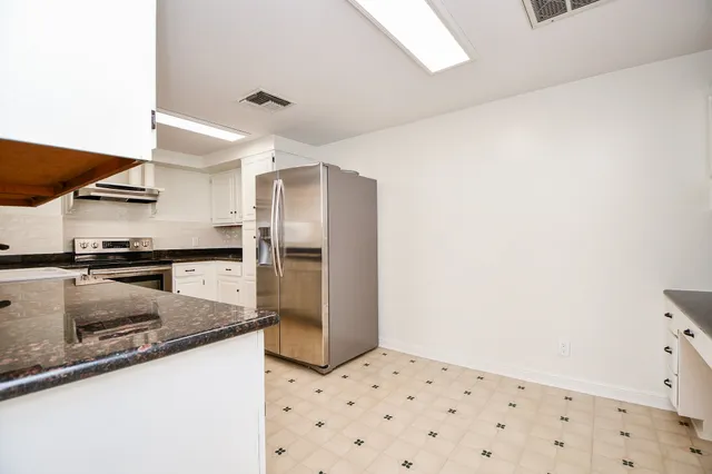 a kitchen with granite countertop a refrigerator and a sink