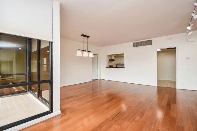 a view of a hallway with wooden floor and a living room