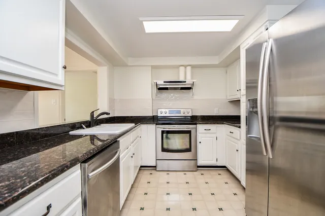 a kitchen with stainless steel appliances granite countertop a sink stove and refrigerator