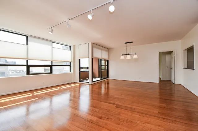 a view of an empty room with window and wooden floor