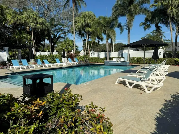 a view of a swimming pool with lawn chairs under an umbrella