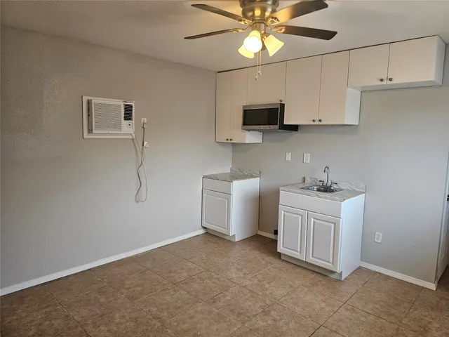 a kitchen with granite countertop a sink a stove top oven and cabinetry
