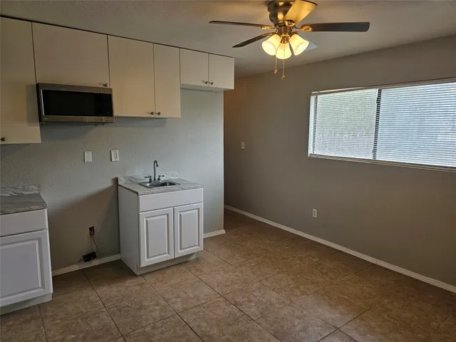 a kitchen with white cabinets appliances and a window