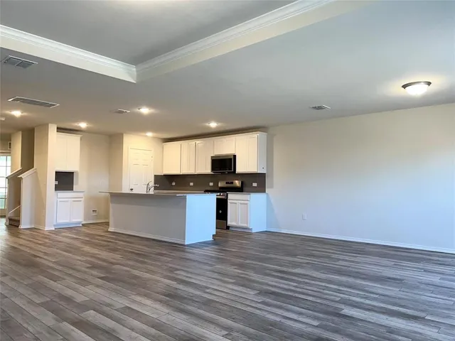 a view of kitchen with kitchen island wooden floor and stainless steel appliances