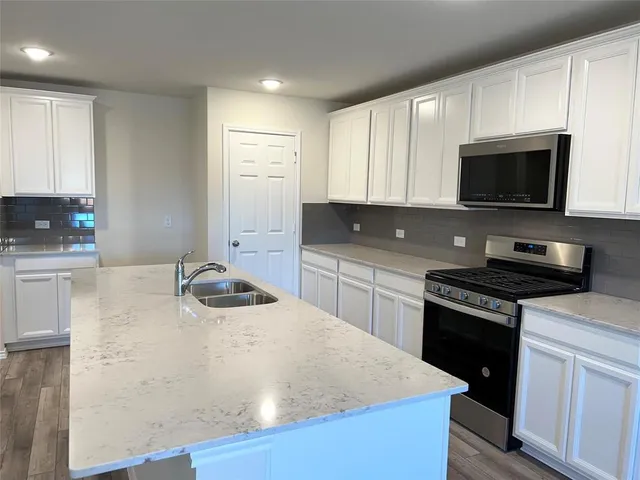 a kitchen with stainless steel appliances a stove a sink a microwave and cabinets
