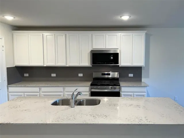 a kitchen with stainless steel appliances granite countertop a sink a stove and a microwave