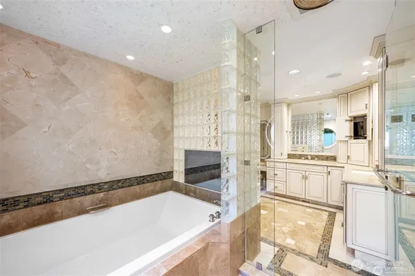 a bathroom with a tub a sink and a large mirror