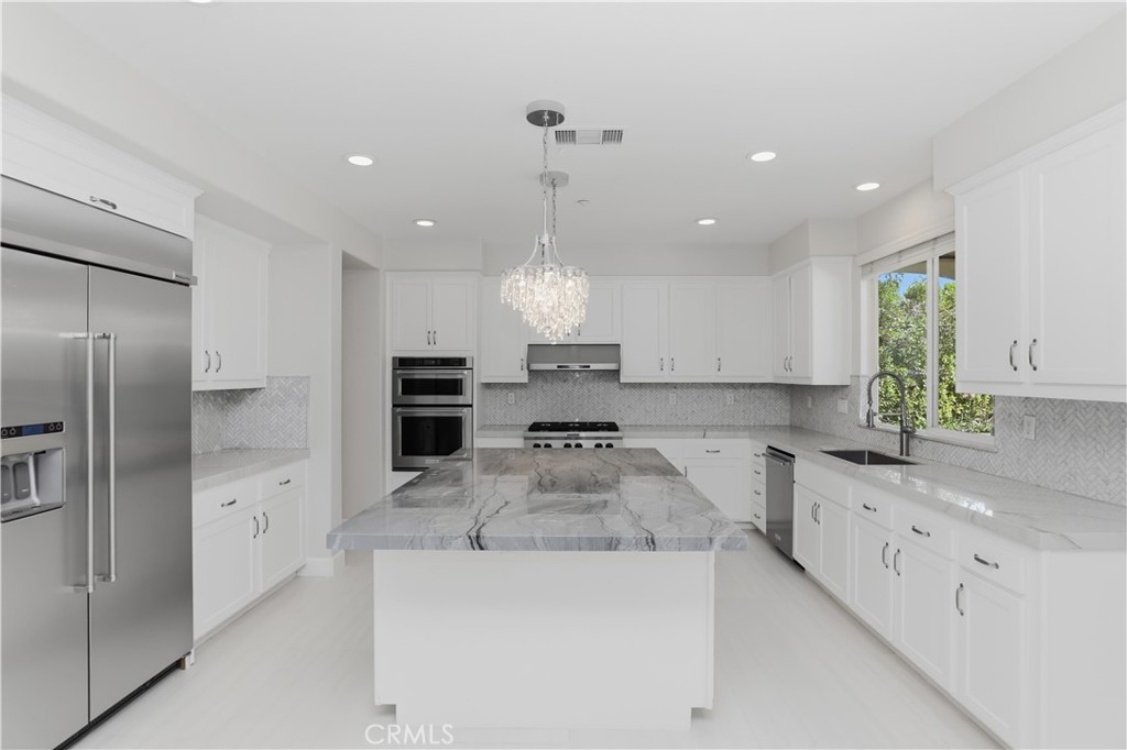 8075 Terraza Court Riverside, CA 92508 - Photo 11 of 75 a large kitchen with stainless steel appliances kitchen island granite countertop a refrigerator a sink dishwasher a stove and white cabinets with wooden floor