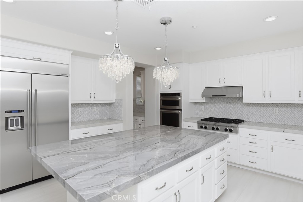 8075 Terraza Court Riverside, CA 92508 - Photo 9 of 75 a kitchen with granite countertop a refrigerator a stove a oven and white cabinets with wooden floor
