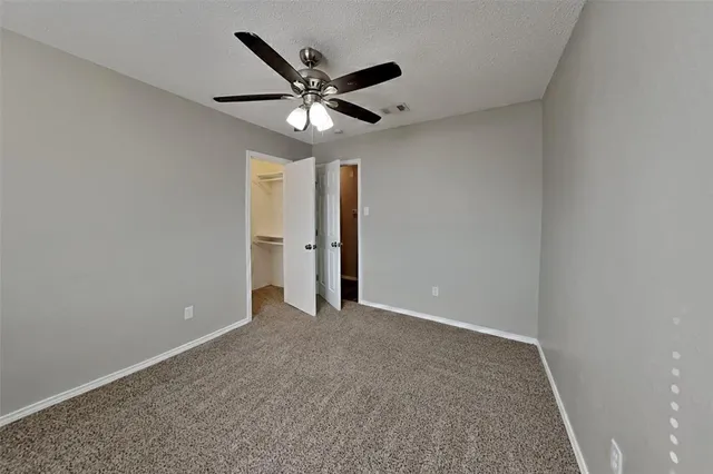 an empty room with closet and a chandelier fan