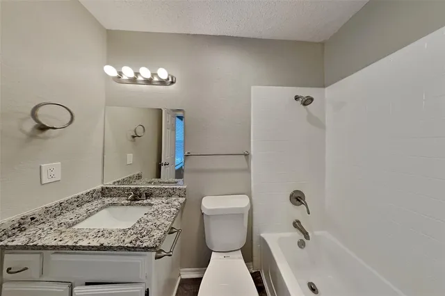 a bathroom with a granite countertop sink a toilet and a mirror