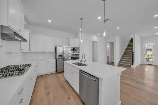 a kitchen with a sink a counter top space stainless steel appliances and cabinets