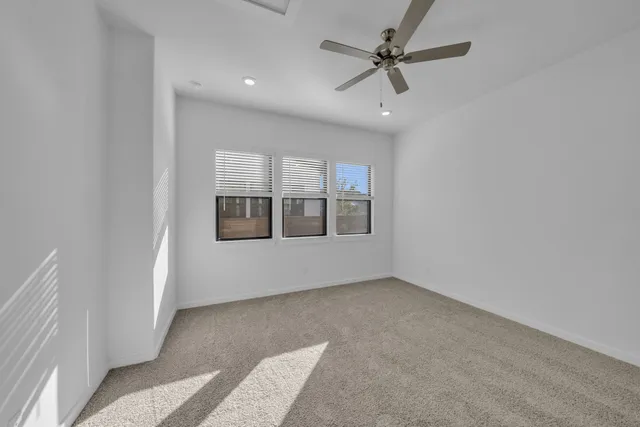 an empty room with windows and ceiling fan