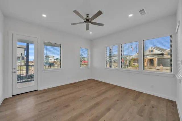 a view of an empty room with a window and wooden floor