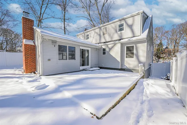 a view of a white house with a large tree