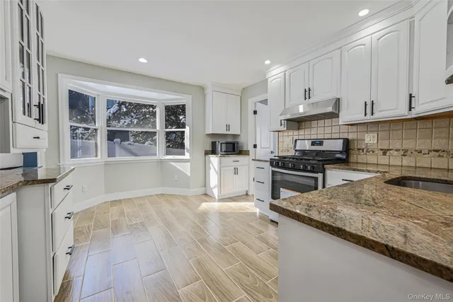 a kitchen with granite countertop a stove a sink and a refrigerator