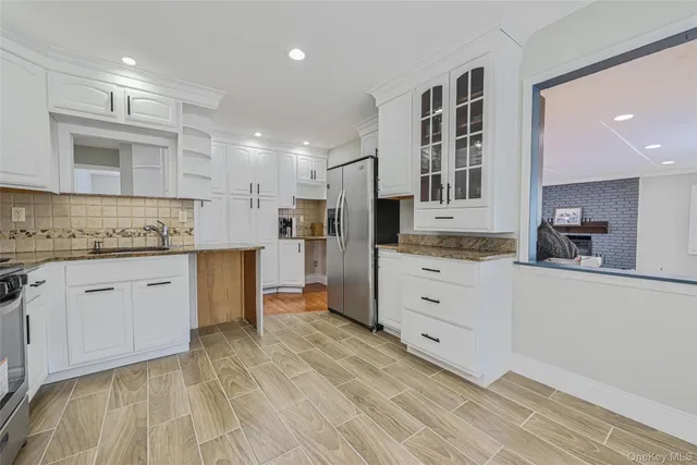 a kitchen with stainless steel appliances kitchen island granite countertop a stove a sink and white cabinets