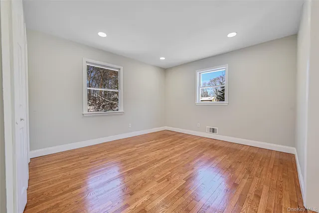 a view of empty room with wooden floor and window